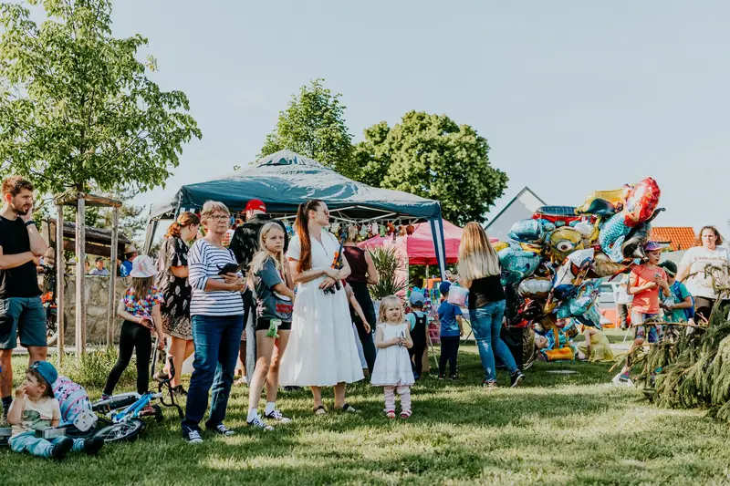 Families with balloons at an outdoor festival on a sunny day